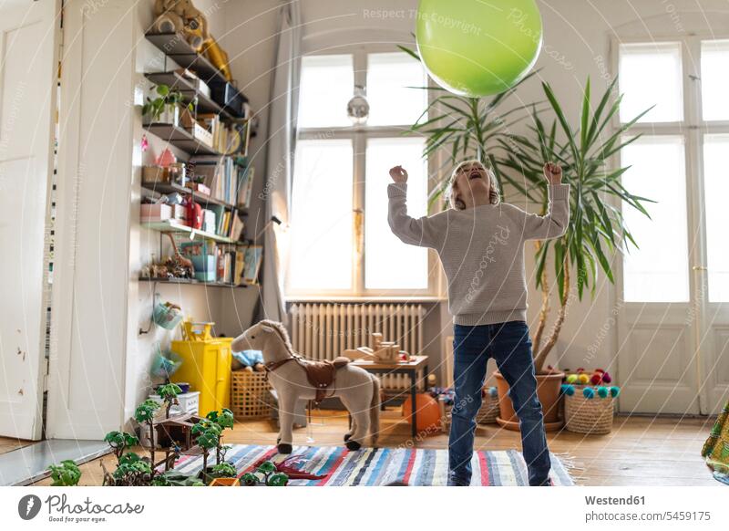Boy playing with a balloon at home balloons windows jumper sweater Sweaters toys balanced Equilibrium delight enjoyment Pleasant pleasure Emotions Feeling