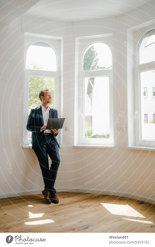 Estate agent waiting in newly refurbished home, holding laptop empty emptiness Businessman Business man Businessmen Business men estate agent real estate agent