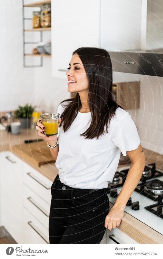 Young woman in kitchen at home drinking glass of orange juice human human being human beings humans person persons celibate celibates singles solitary people