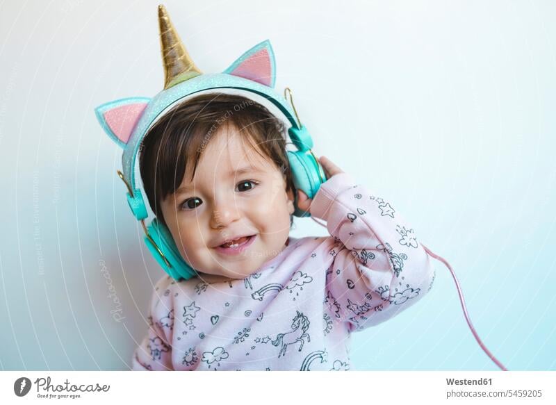 Portrait of smiling baby girl with unicorn headphones listening music headset smile infants nurselings babies hearing baby girls female people persons