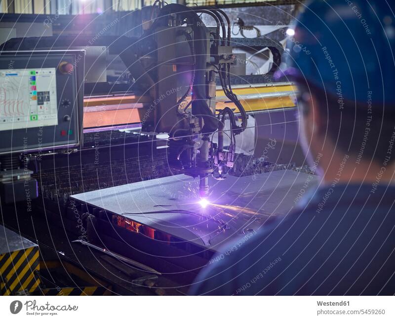 Worker looking to laser cutter Eastern European Etnicity spark sparks industry industrial laser cutting Job Occupation metal metals laser beam laser beams plant