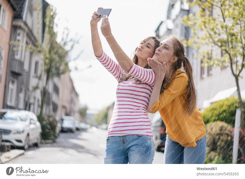 Girlfriends taking selfie in the city female friends Selfie Selfies Smartphone iPhone Smartphones photographing town cities towns mate friendship mobile phone