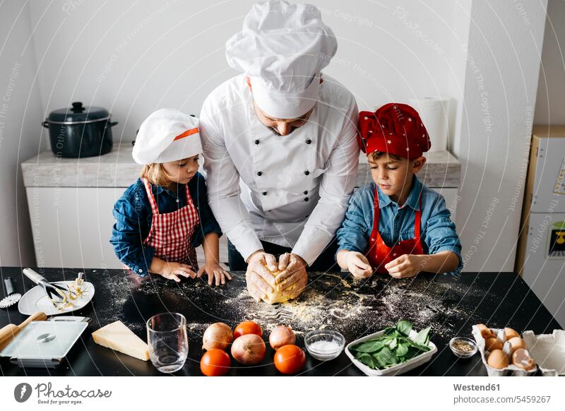 Father with two kids preparing homemade gluten free pasta in kitchen at home Chefs cook cooks learn funny having fun supporting Co-Operation collaborate