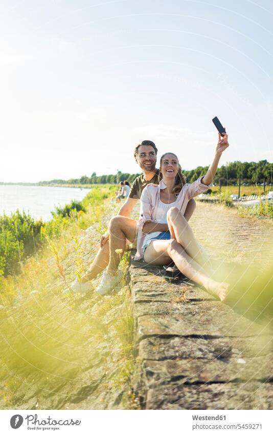 Happy couple at the riverside in summer taking a selfie happiness happy riverbank Selfie Selfies summer time summery summertime River Rivers twosomes