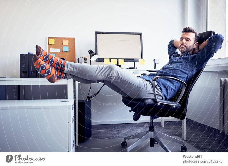 Man sitting at desk in office having a power nap offices office room office rooms Seated man men males workplace work place place of work Adults grown-ups