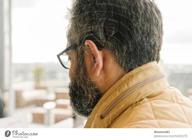 Profile of a man with cochlear implant coat coats jackets Eye Glasses Eyeglasses specs spectacles hear Social Issue Social Theme Social Themes Social Topic