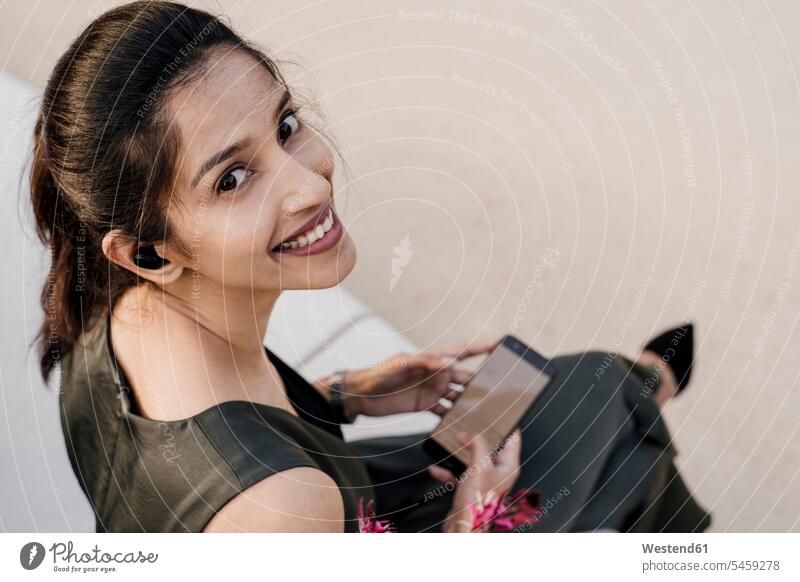 Close-up of smiling female professional using mobile phone while sitting on seat color image colour image Spain outdoors location shots outdoor shot