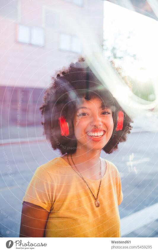 Portrait of happy young woman with afro hairdo listening to music with headphones in the city human human being human beings humans person persons curl curled