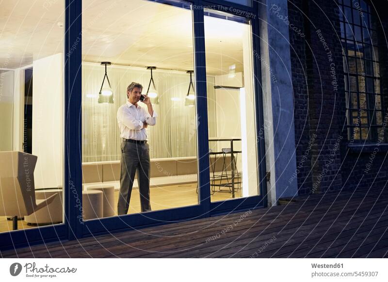Exterior view of man using smartphone in modern building at night Smartphone iPhone Smartphones exterior exterior view Businessman Business man Businessmen