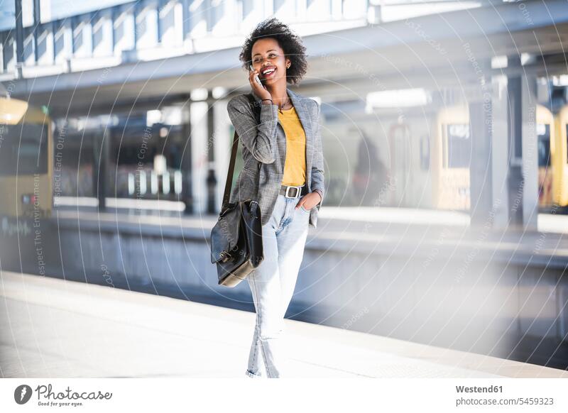 Happy young woman on the phone at the train station business life business world business person businesspeople business woman business women businesswomen