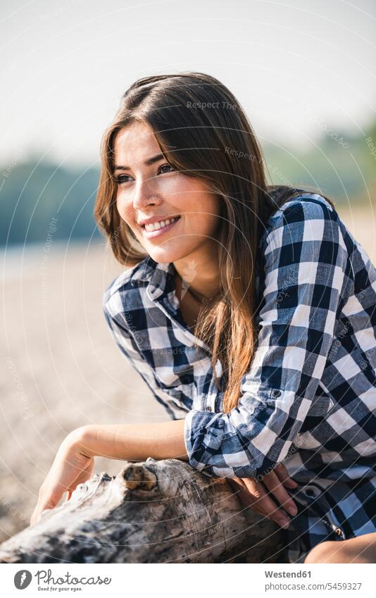 Smiling young woman sitting outdoors smiling smile Seated portrait portraits females women Adults grown-ups grownups adult people persons human being humans
