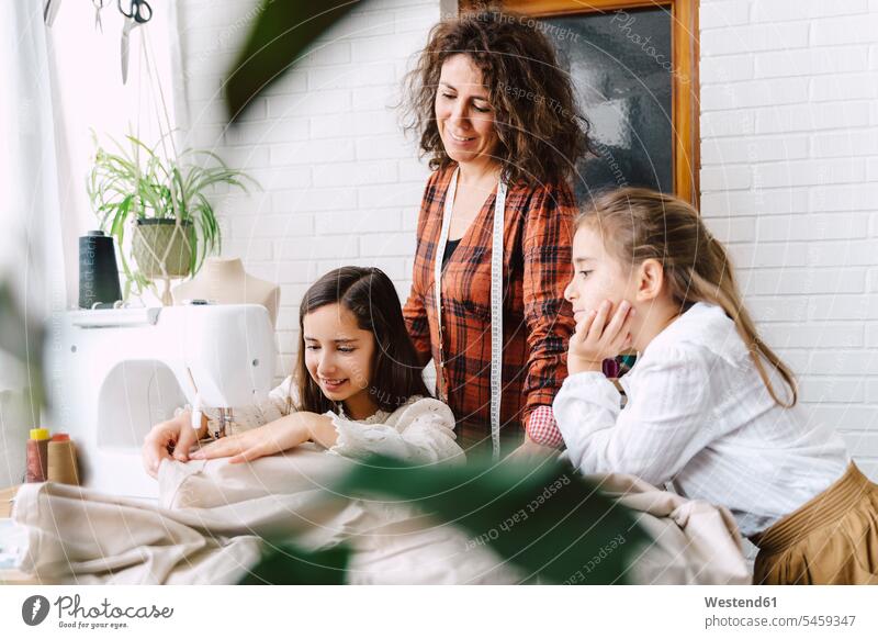 Mother and two daughters sewing at home Measure Tape measuring tape measuring tapes tape measures Tables textiles cloth fabrics learn smile delight enjoyment