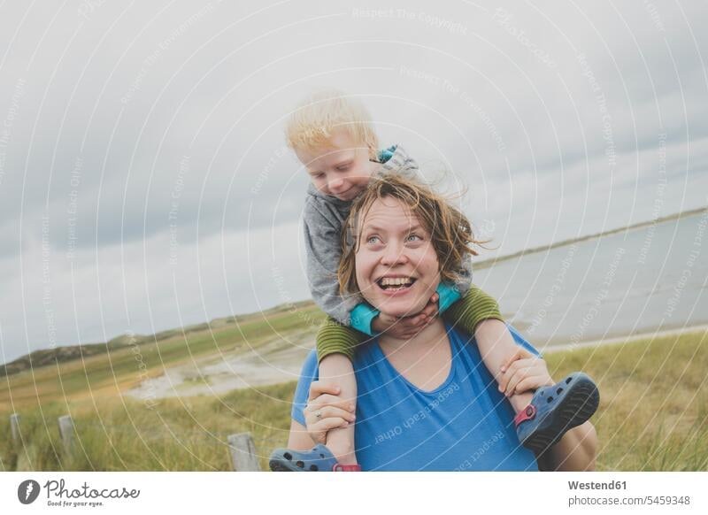Portrait of happy mother carrying little daughter on her shoulders, Sylt, Germany human human being human beings humans person persons caucasian appearance