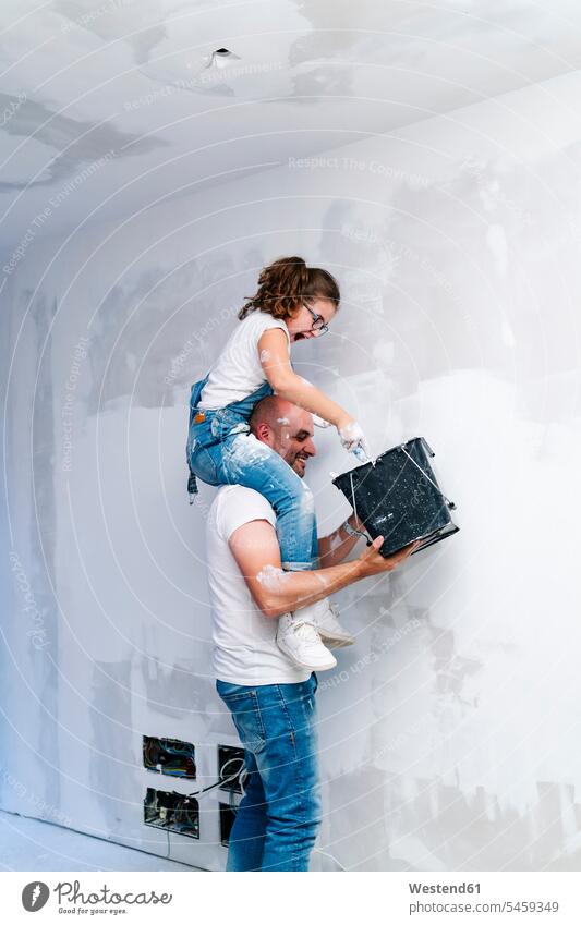 Girl sitting on father's shoulders painting the wall of her new house pants Trouser Denim Jeans T- Shirt t-shirts tee-shirt At Work work hold smile