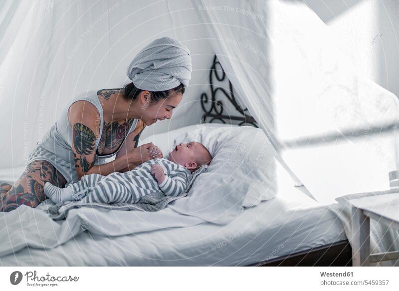 Tattooed young woman with her baby in canopy bed human human being human beings humans person persons Mixed Race mixed race ethnicity mixed-race Person 2