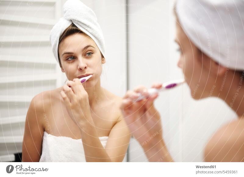 Mirror image of young woman in bathroom brushing her teeth females women mirror image reflexion reflection tooth Bath Domestic Bathroom bath room Adults