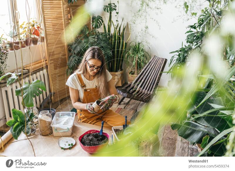 Young woman working with soil in a small gardening shop Occupation Work job jobs profession professional occupation flower pot flower pots flowerpots Tables