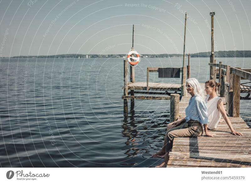Mother and daughter sitting on jetty, relaxing at the sea human human being human beings humans person persons caucasian appearance caucasian ethnicity european