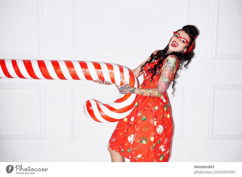 Portrait of tattooed woman having fun with oversized candy cane candy canes Sugar Canes females women Fun funny tattoos portrait portraits humongous gigantic