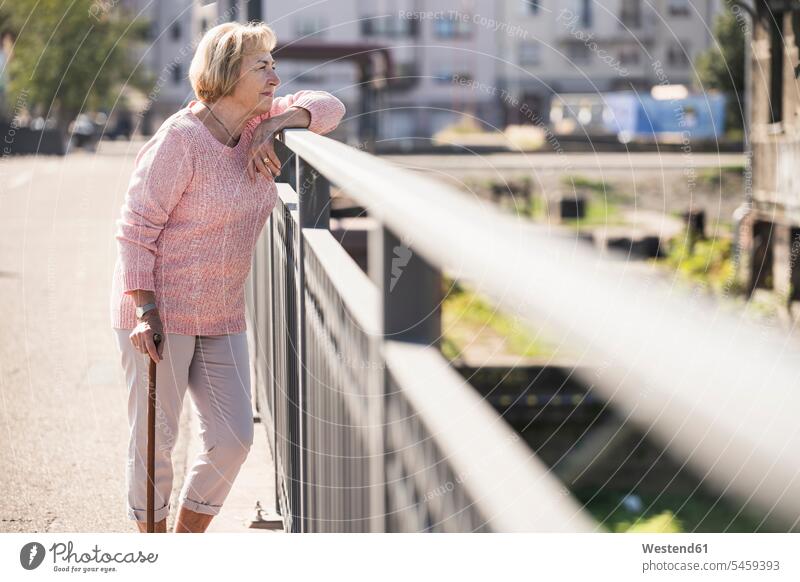 Senior woman walking on footbridge, using walking stick jumper sweater Sweaters go going hold smile delight enjoyment Pleasant pleasure happy aspirations Crave