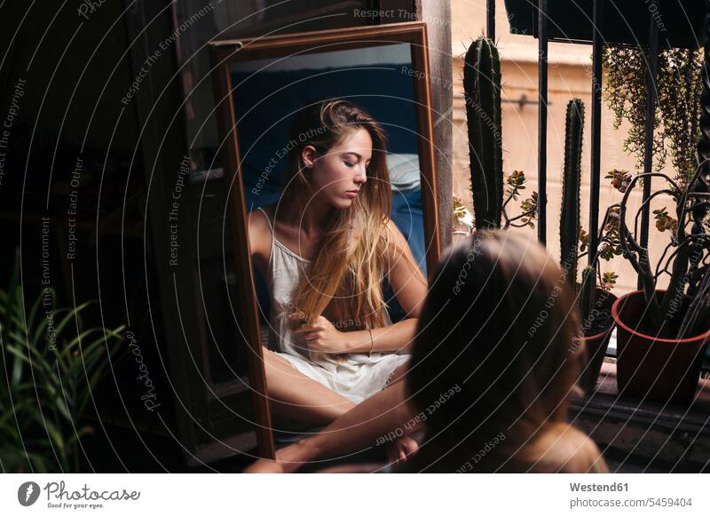 Mirror image of young woman sitting on the floor at home relaxing relaxation mirror image reflexion reflection females women Seated Floor Floors Adults