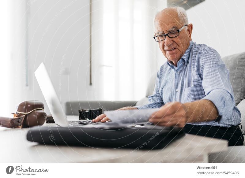 Senior man working with a computer and his old photo cameras and old photos using use wireless Wireless Connection Wireless Technology Wireless Communication
