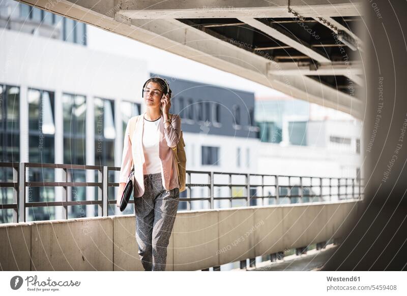 Young businesswoman walking in parking garage, listeing music with her headphones occupation profession professional occupation jobs day daylight shot