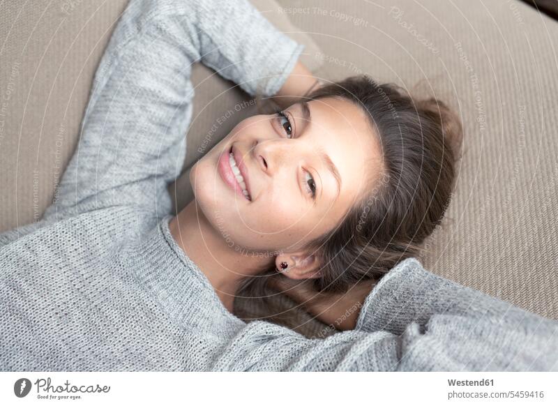 Portrait of smiling woman lying on couch females women settee sofa sofas couches settees laying down lie lying down smile portrait portraits Adults grown-ups