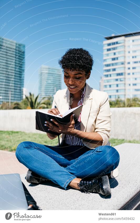 Woman writing notes in a notebook sitting on a bench business life business world business person businesspeople business woman business women businesswomen