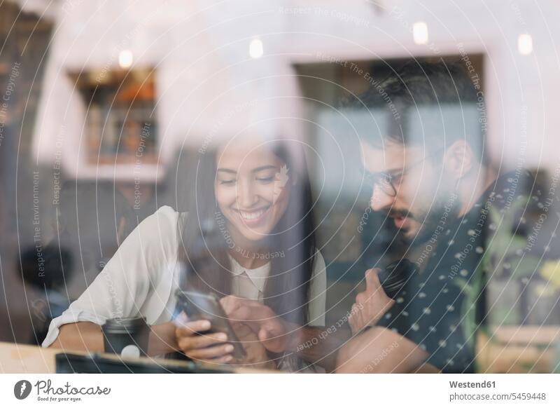 Young couple with smartphone behind windowpane in a cafe human human being human beings humans person persons caucasian appearance caucasian ethnicity european
