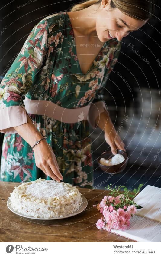 Smiling young woman garnishing home-baked cake smiling smile females women Adults grown-ups grownups adult people persons human being humans human beings