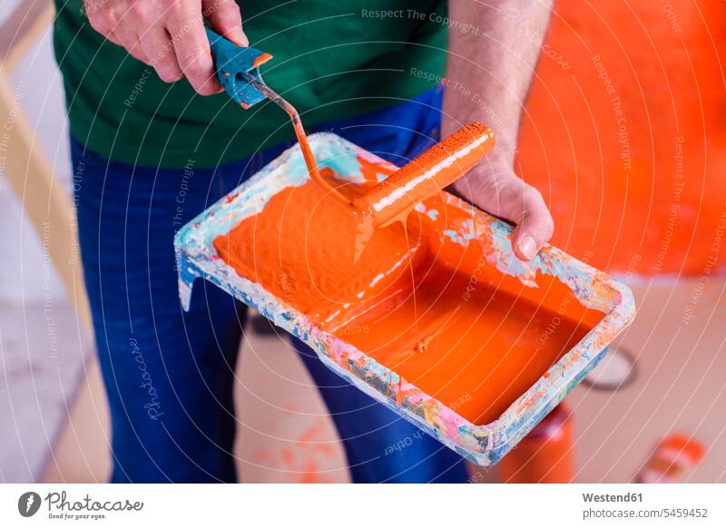 Close-up of man holding paint tray with orange paint human human being human beings humans person persons caucasian appearance caucasian ethnicity european 1