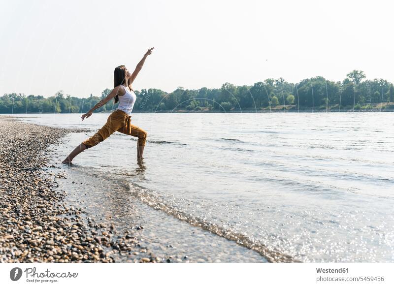 Young woman standing in water of a river practicing yoga Yoga females women River Rivers Adults grown-ups grownups adult people persons human being humans