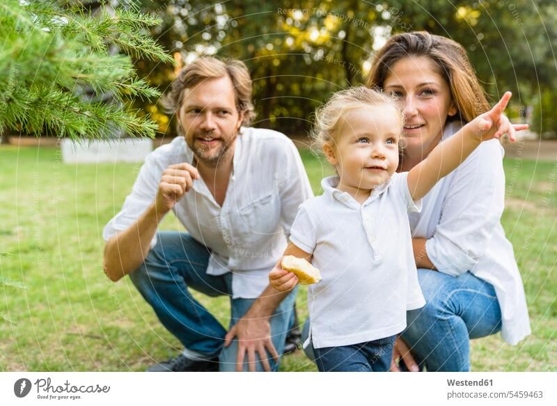 Parents with little daughter pointing her finger on a meadow human human being human beings humans person persons caucasian appearance caucasian ethnicity