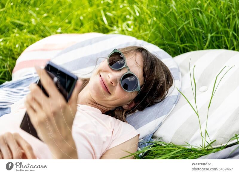 Relaxed woman lying on a meadow using cell phone human human being human beings humans person persons caucasian appearance caucasian ethnicity european 1