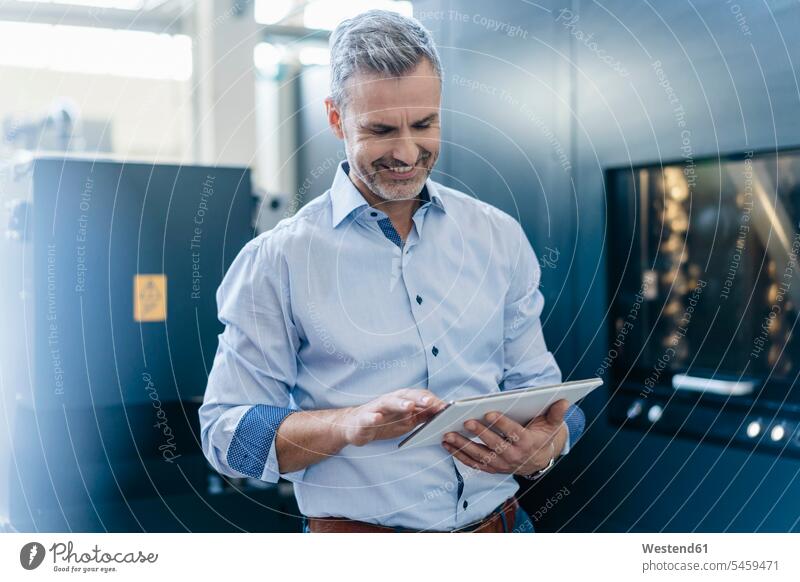Smiling businessman using a tablet in a factory human human being human beings humans person persons caucasian appearance caucasian ethnicity european 1