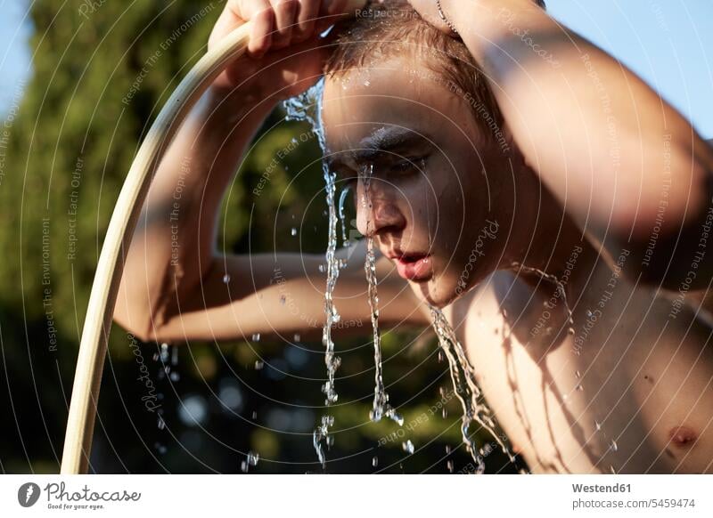 Teenage boy refreshing with water from garden hose Refreshment Gardening Hose hosepipe hosepipes Teenager Teens teenagers people persons human being humans