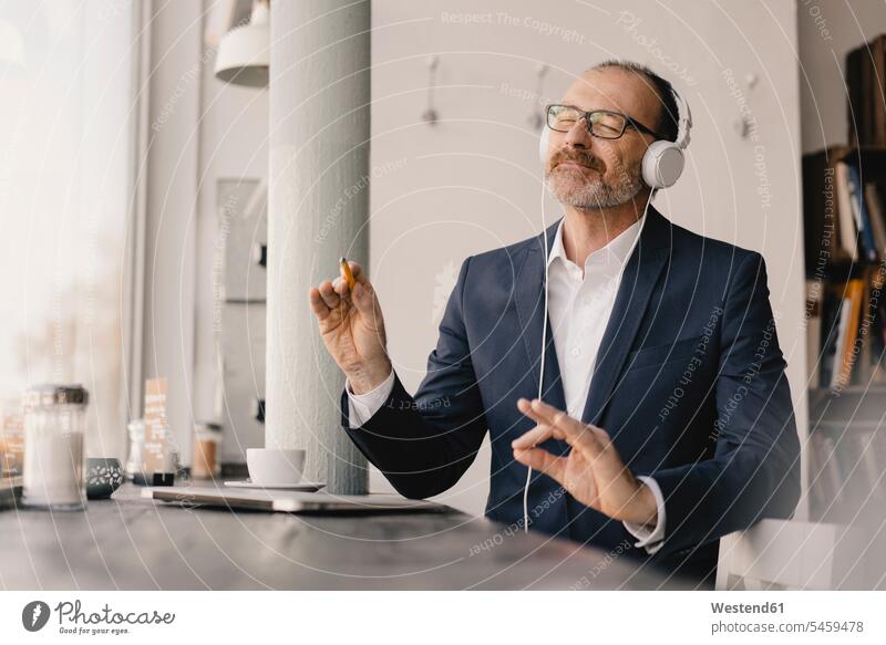 Mature businessman with closed eyes listening to music with headphones human human being human beings humans person persons caucasian appearance