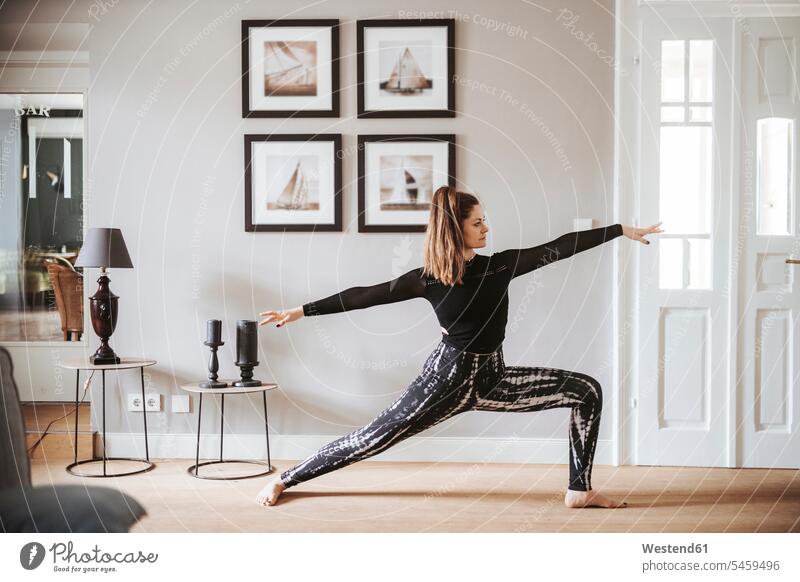 Woman practising yoga at home, warrior pose free time leisure time Sport Training Move Movement moving floor land location shot location shots outdoor