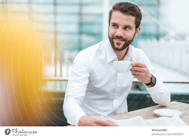 Smiling young businessman with newspaper and cup of coffee in a cafe Coffee smiling smile Coffee Cup Coffee Cups newspapers Businessman Business man Businessmen