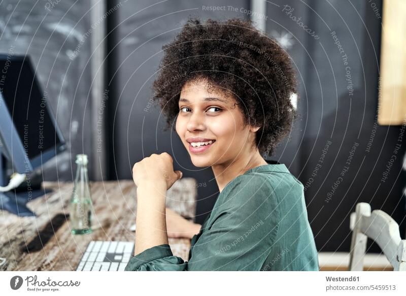 Portrait of smiling young woman at wooden table in office smile offices office room office rooms females women portrait portraits Table Tables workplace