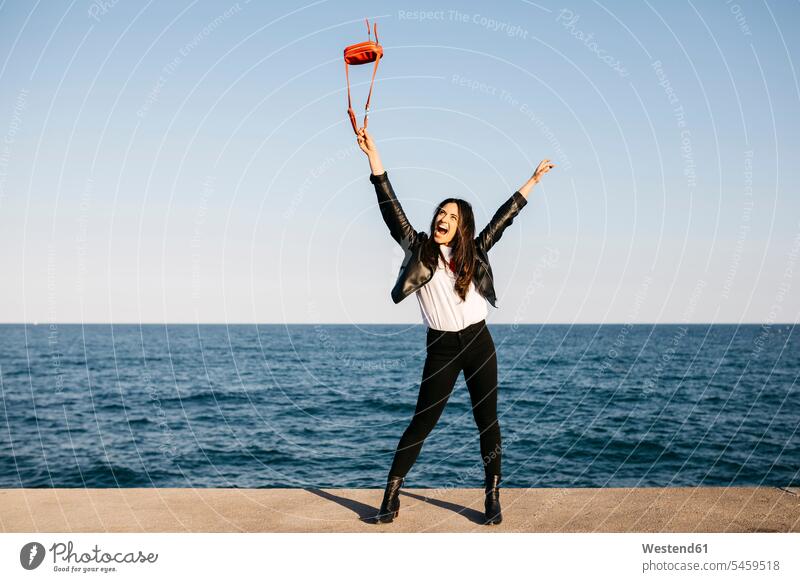 Happy woman playing with red bag, the sea in the background smiling smile females women journey travelling Journeys voyage Adults grown-ups grownups adult