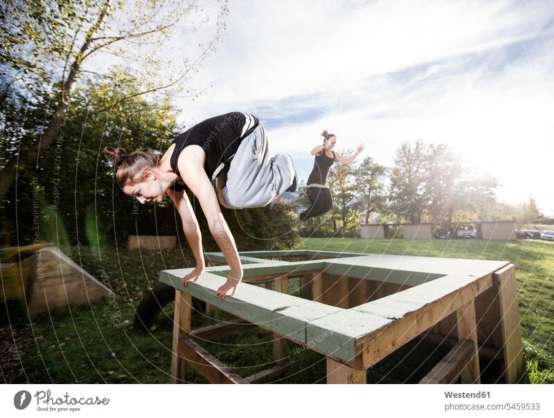 Woman jumping over barrier during freerunning exercise woman females women exercises obstacle obstacles Leaping Freerunning Adults grown-ups grownups adult