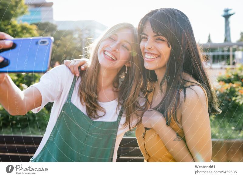 Portrait of two happy friends taking selfie with smartphone mate female friend jewelry telecommunication phones telephone telephones cell phone cell phones
