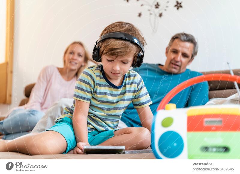 Family on couch at home with boy listening to music with headphones couches settee settees sofa sofas toys headset radios CD ROM CD-ROM CDs Compact Disc