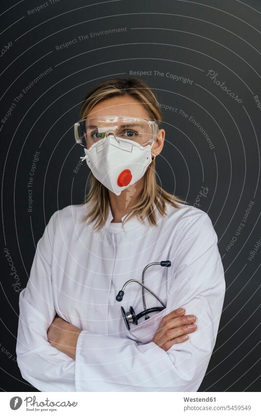 Portrait of doctor wearing FFP3 mask and safety glasses against grey background Occupation Work job jobs profession professional occupation work cloth