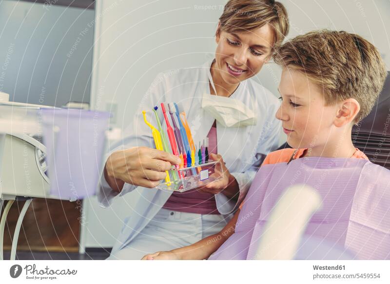 Dentist examining boy's teeth with dental instruments boys males tooth cleaning toothbrush tooth-brushes toothbrushes patient patients explaining female dentist