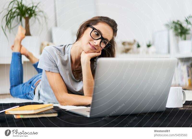 Young woman at home lying on the floor using laptop Laptop Computers laptops notebook laying down lie lying down females women floors computer computers Adults