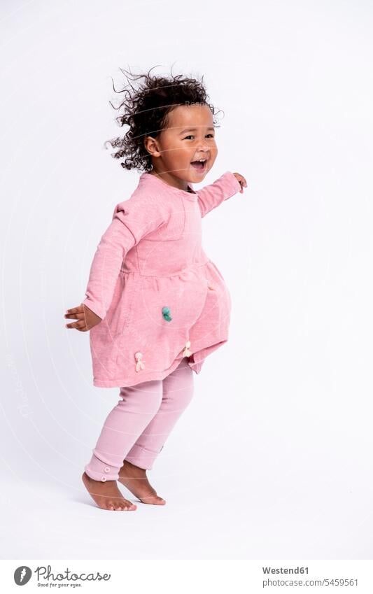 Portrait of barefoot little girl dressed in pink hopping in front of white background dresses jumps Leaping delight enjoyment Pleasant pleasure Cheerfulness