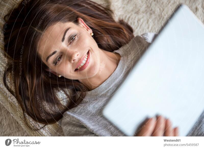 Smiling woman lying on carpet using a tablet laying down lie lying down digitizer Tablet Computer Tablet PC Tablet Computers iPad Digital Tablet digital tablets